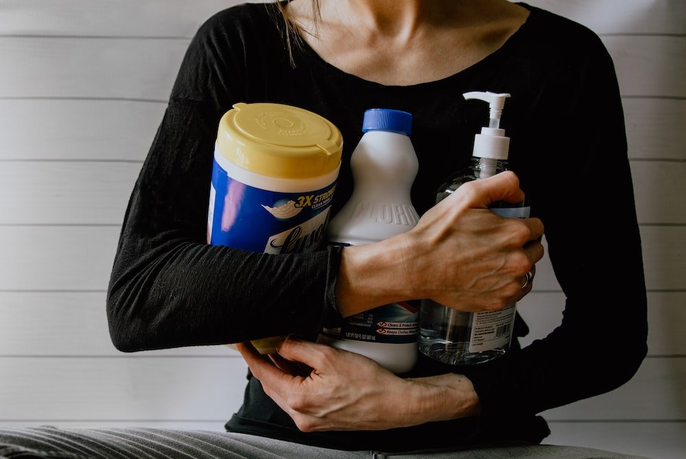 Cropped photo of a person holding cleaning solutions