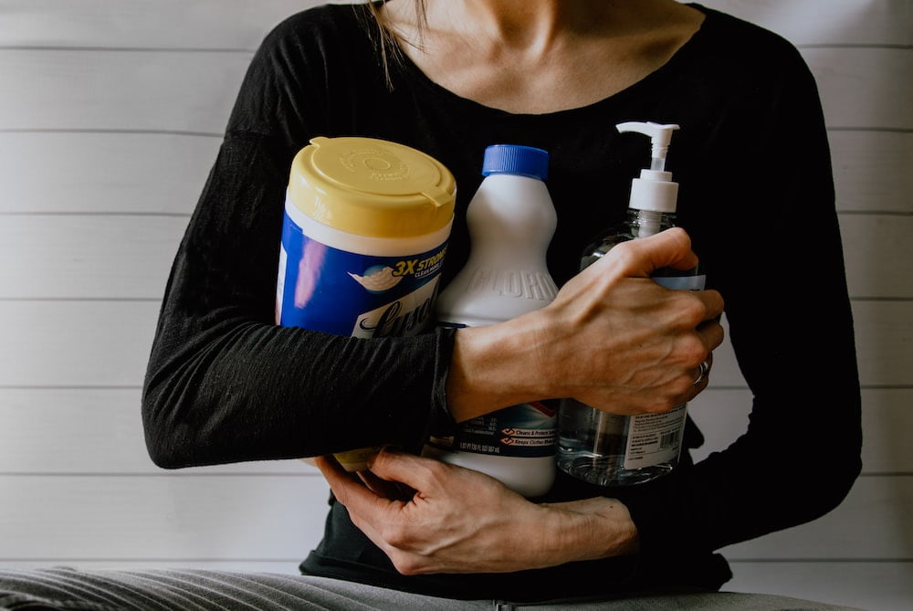 Cropped photo of a person holding cleaning solutions