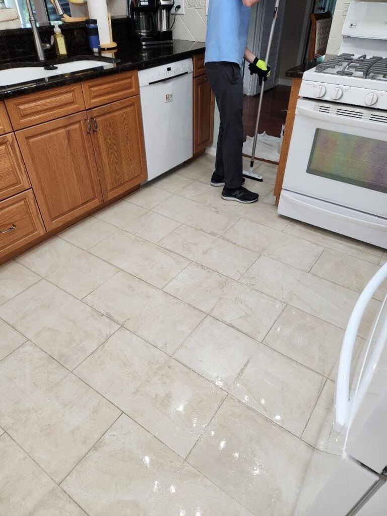 An image of a man cleaning tiles with a floor wiper