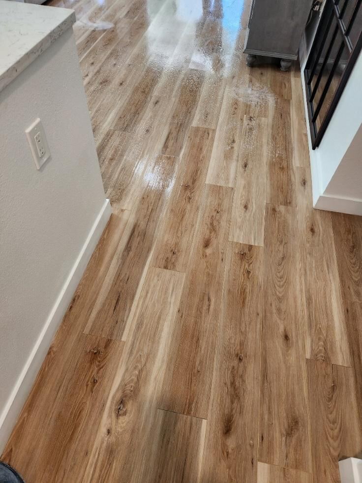 A technician performing steam-based hardwood cleaning in a client’s home