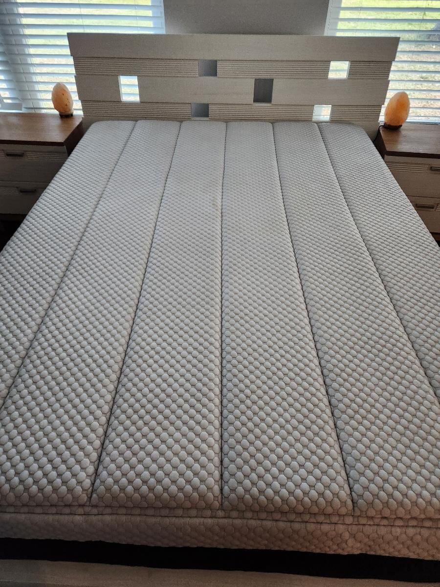 A freshly cleaned mattress is neatly placed on a bed frame between two nightstands, suggesting recent upholstery or deep cleaning work.