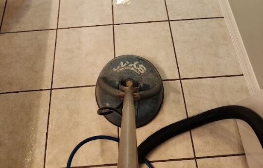 A professional tile and grout cleaning machine is being used on a tiled floor