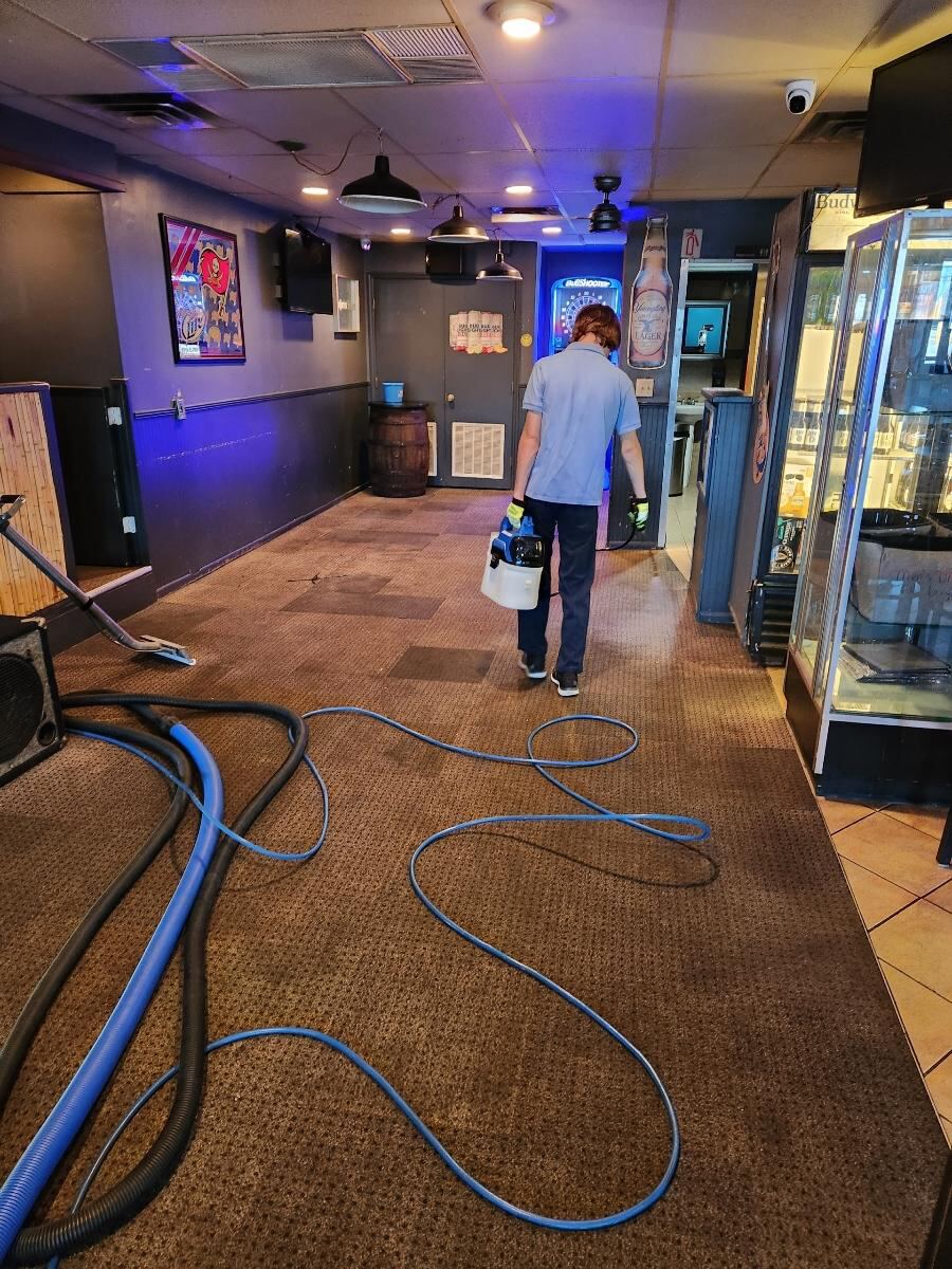 Worker applying pre-treatment for stains on commercial carpet.