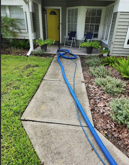Professional cleaning hose entering a home through the doorway.