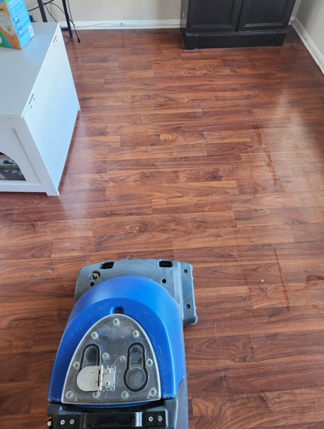 Professional floor cleaning machine restoring rich-toned hardwood flooring in a residential room