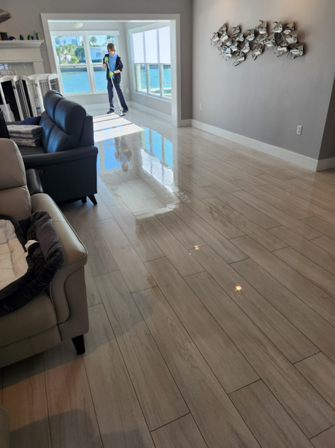 Technician cleaning glossy tile flooring in a bright living room with professional equipment