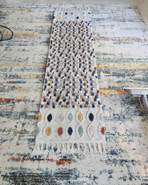 Area rug with visible stains being cleaned using extraction tool