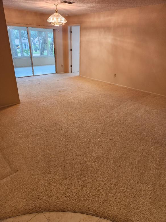 This photo shows a clean carpeted room with soft light entering from windows.