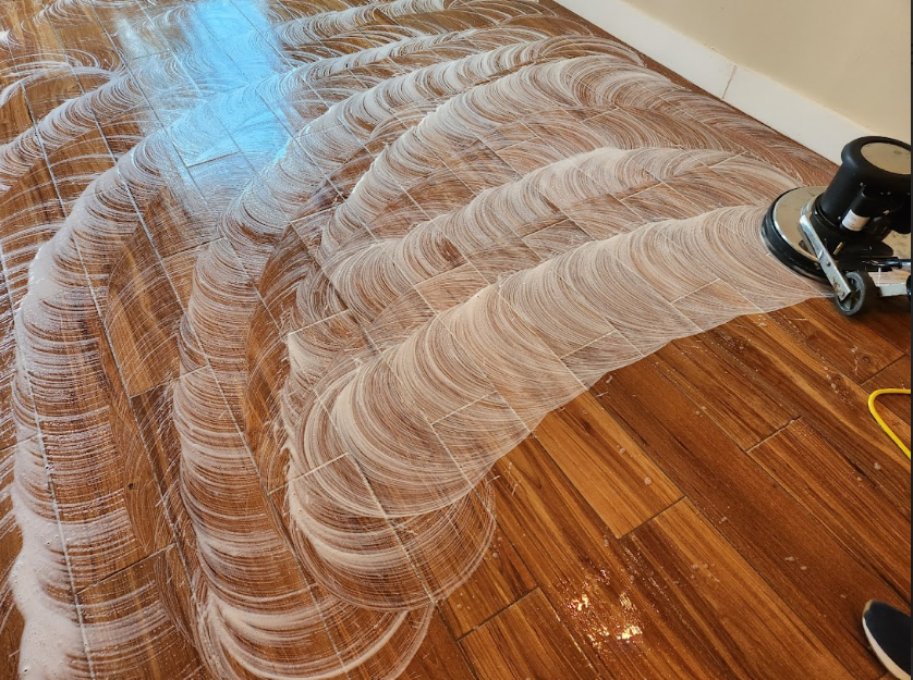 Hardwood floor being scrubbed and polished with a cleaning machine during deep cleaning