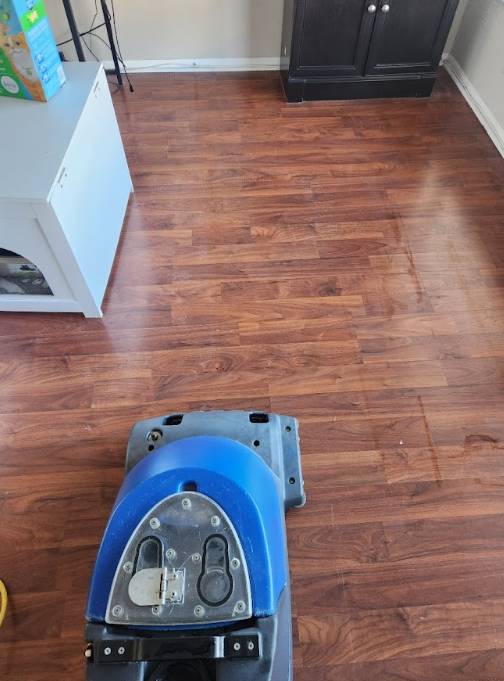 Steam cleaning machine being used on a hardwood floor in a residential room