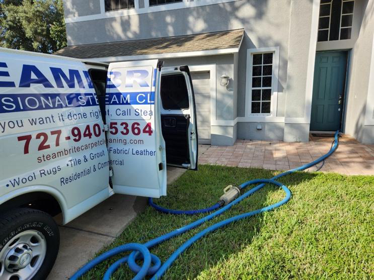 This photo shows an open cleaning van with steam pipes going inside a home.