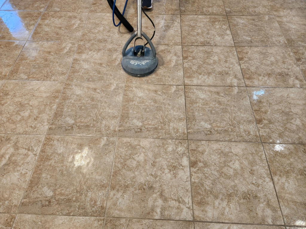 a cleaner using a rotary scrubber to clean grout lines between tiles