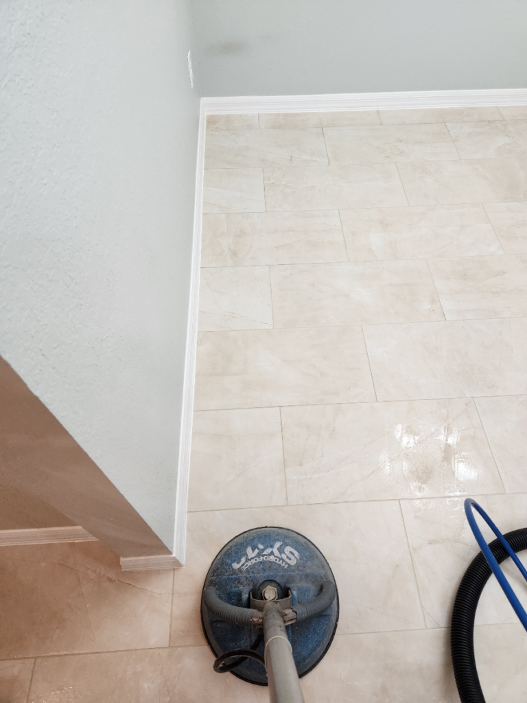 a cleaner cleaning tiles using a rotary scrubber