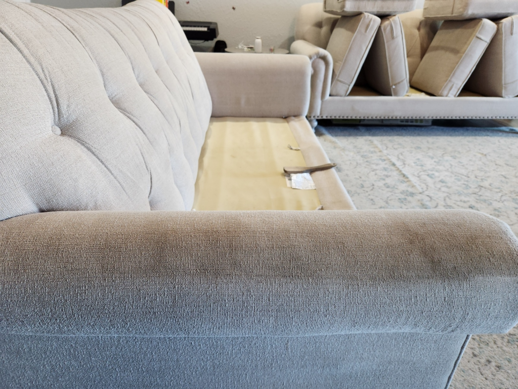 a sofa placed on a carpet with its cushions taken out for cleaning