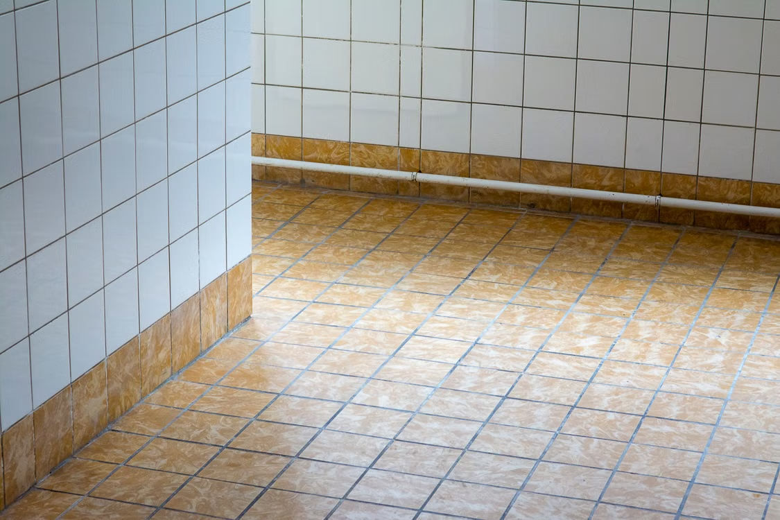 A floor with grimey tiles.