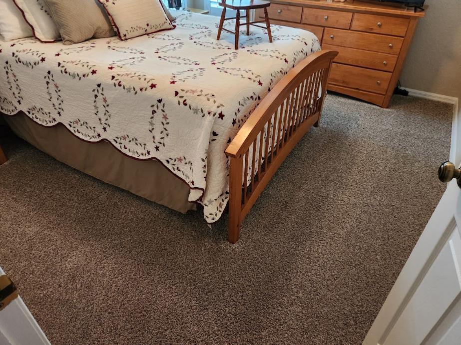 A bedroom with a bed, a dresser, and a carpet