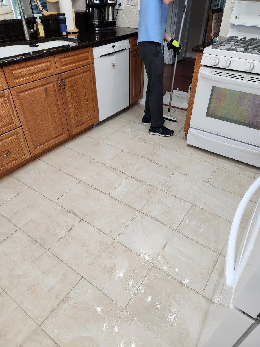 a person wearing gloves mopping the floor of the kitchen