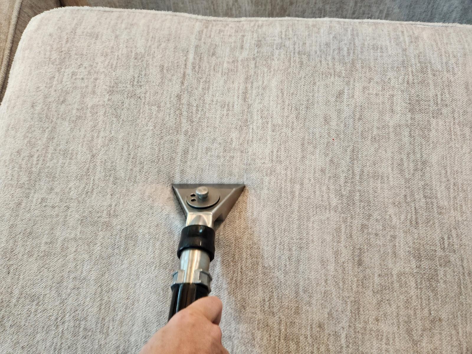 close-up of a person vacuuming a sofa cushion